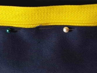 close up of one zipper arm pinned onto margin of panel