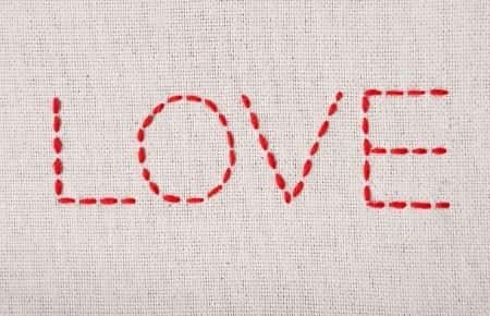 love embroidered with red thread on taupe background